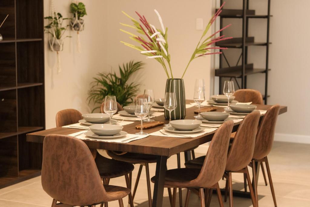 Wooden dining table set with plates and glasses, beside a dark display cabinet