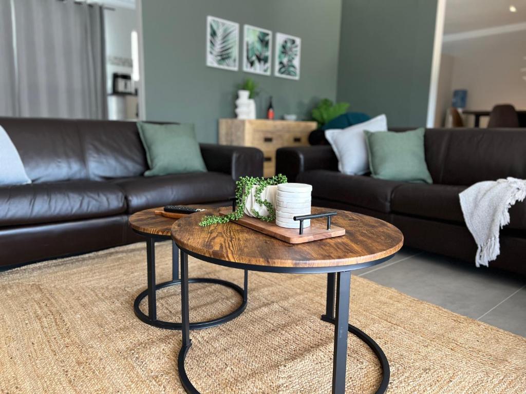 Villa lounge with dark sofas, round wooden coffee tables and botanical artwork